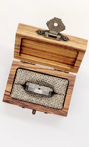 Tungsten memorial ring with ashes inlay in a wooden box with metal clasp.