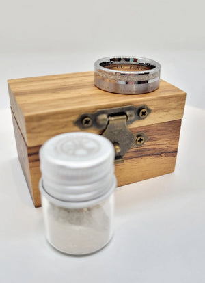 Memorial ring on wooden box with jar of ashes; tungsten ring, engraved, 8mm wide, with ashes inlay for remembrance.  