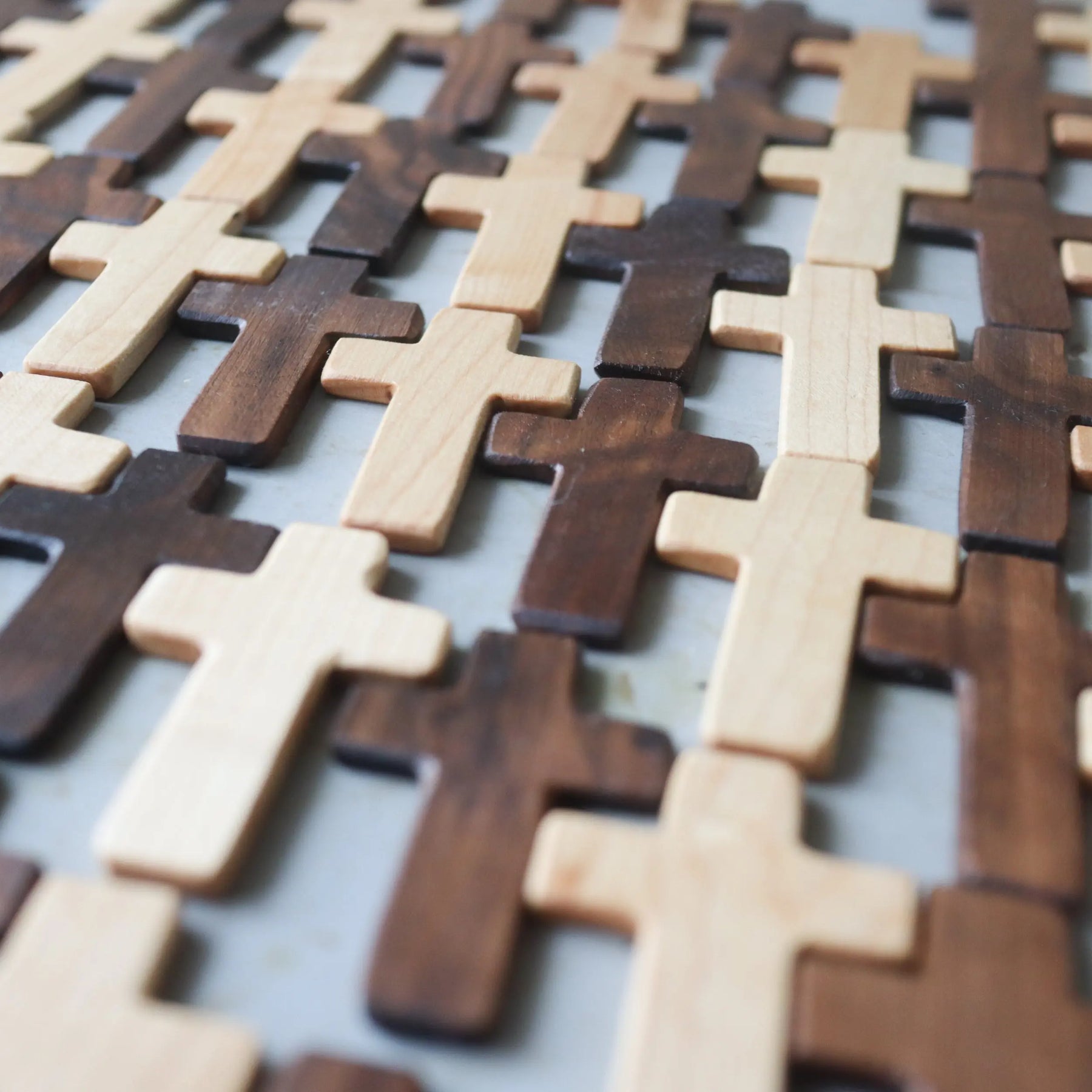 Wooden crosses in light and dark wood arranged in a grid pattern.