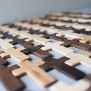 Wooden pocket crosses in light and dark brown arranged in a grid.