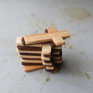 Stack of thin wooden pocket crosses in alternating light and dark wood colors.