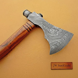 Damascus steel axe head with wood handle on rustic wood surface