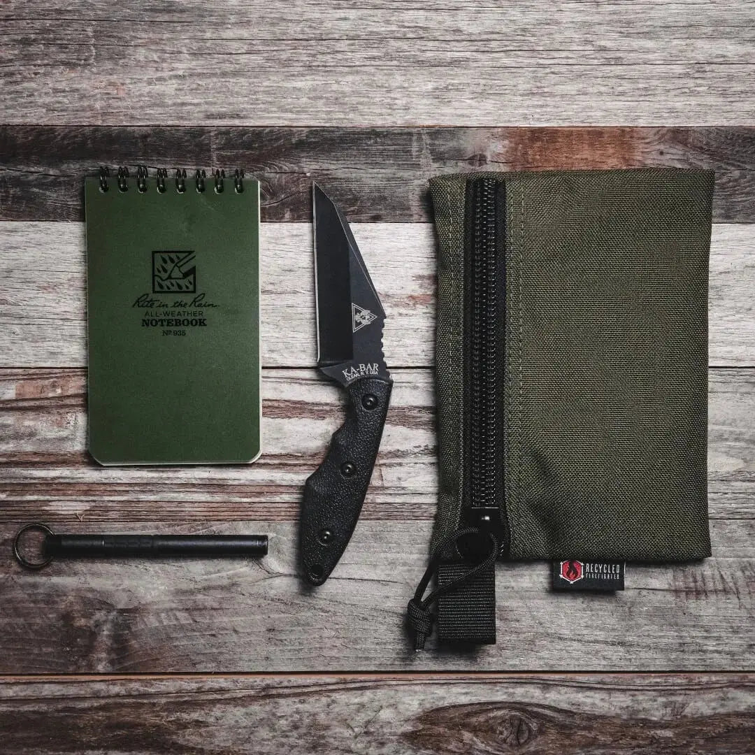 Olive green pouch, notebook, and knife on a wooden surface.