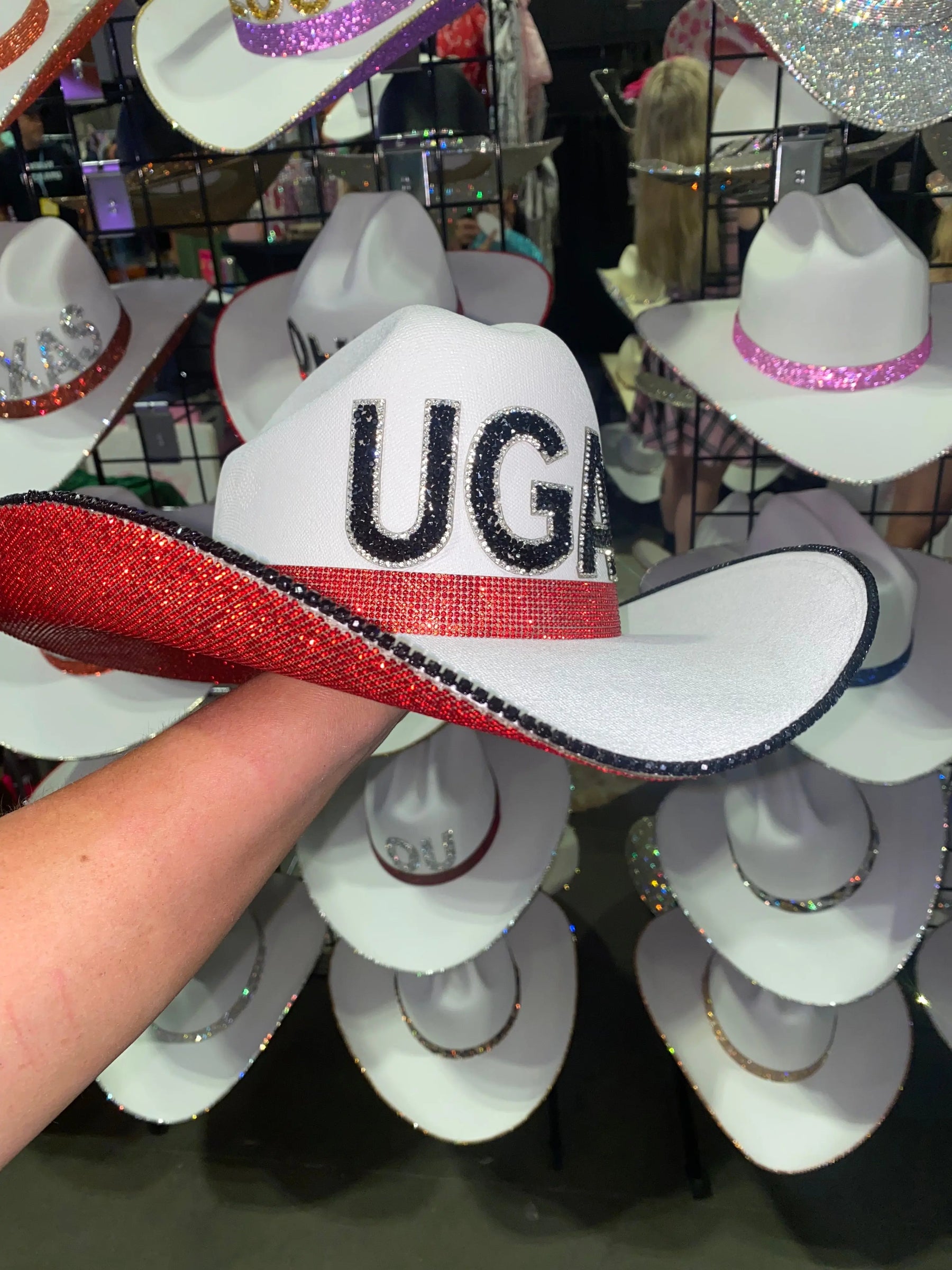 White straw cowboy hat with red and black rhinestones and 'UGA' letters.