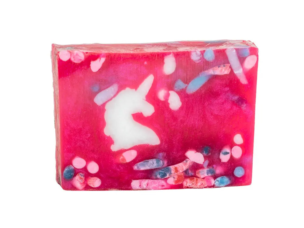 Pink rectangular soap bar with a white unicorn shape and colorful inclusions.