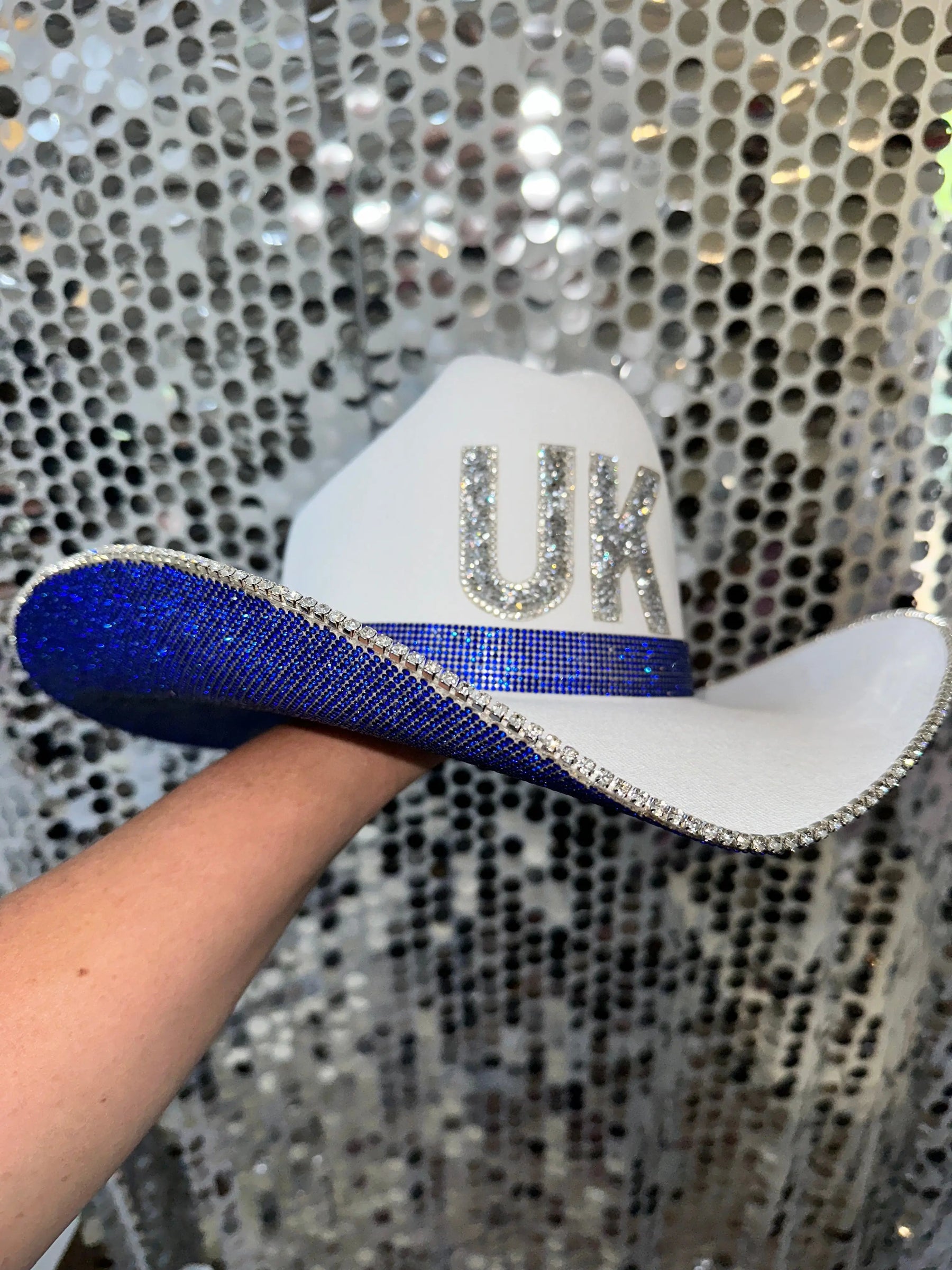 University of Kentucky cowboy hat with white crown, blue rhinestone brim, and "UK" letters.