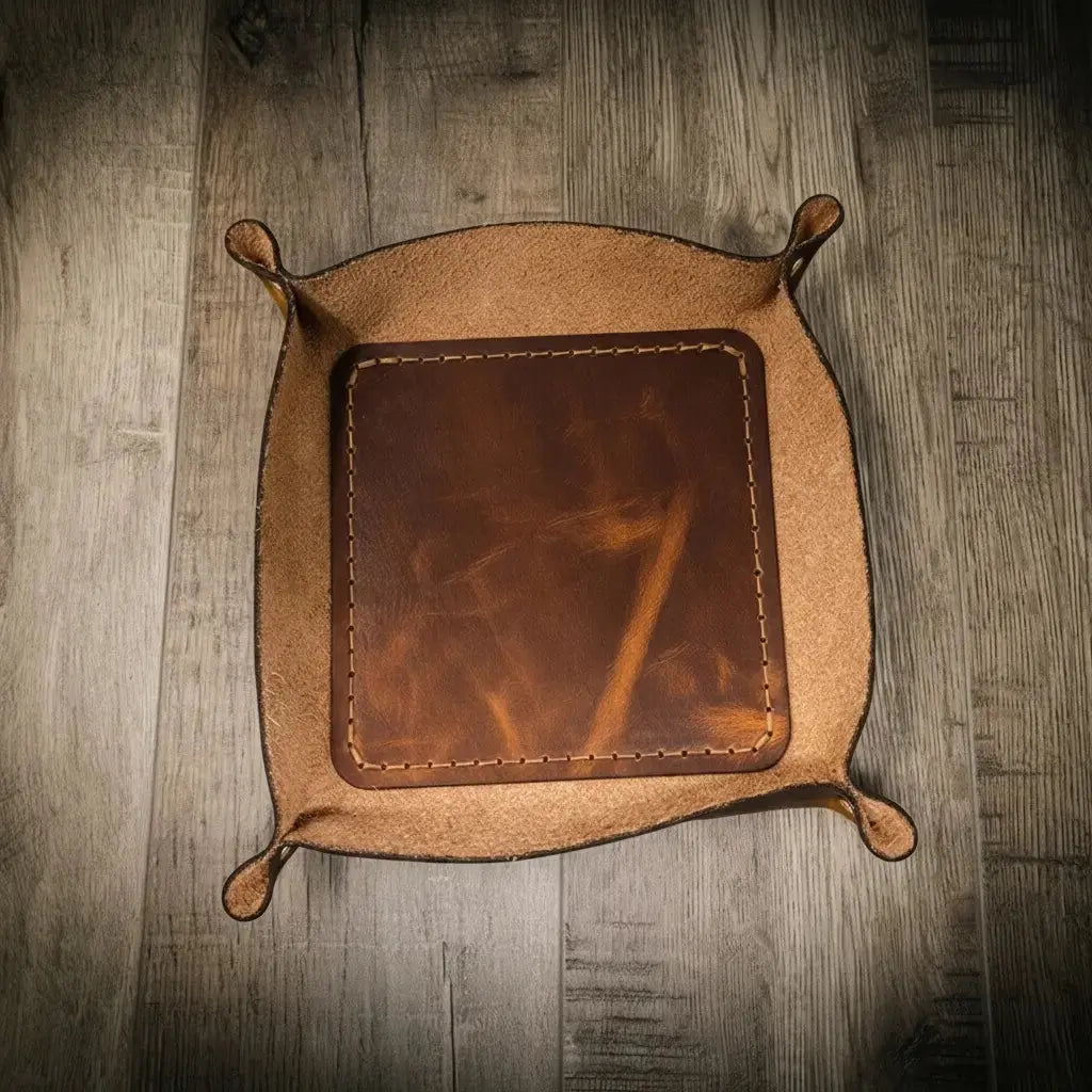 Brown leather valet tray with stitched edges on a wooden surface.