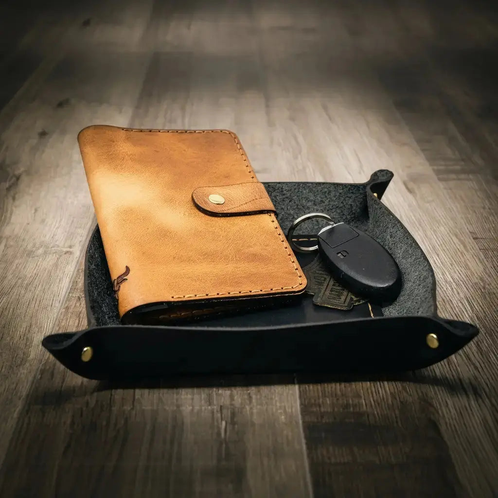 Leather valet tray holding a brown wallet and car keys on a wooden surface.