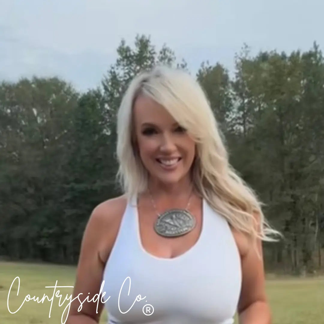 Woman in white tank top wearing a rustic buckle necklace outdoors