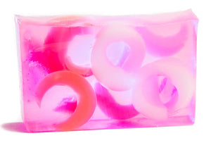 Pink and clear soap bar with pink and white ring-shaped embeds, on a white background.