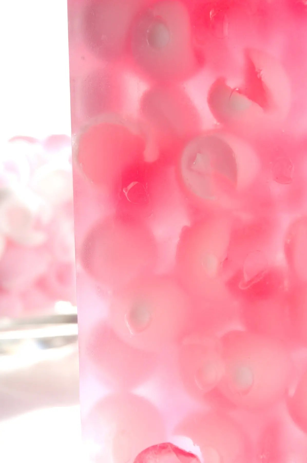 Pink translucent soap slice with visible rose petals.