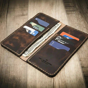 Brown leather bifold wallet with multiple card slots and cash shown open on a wooden surface.