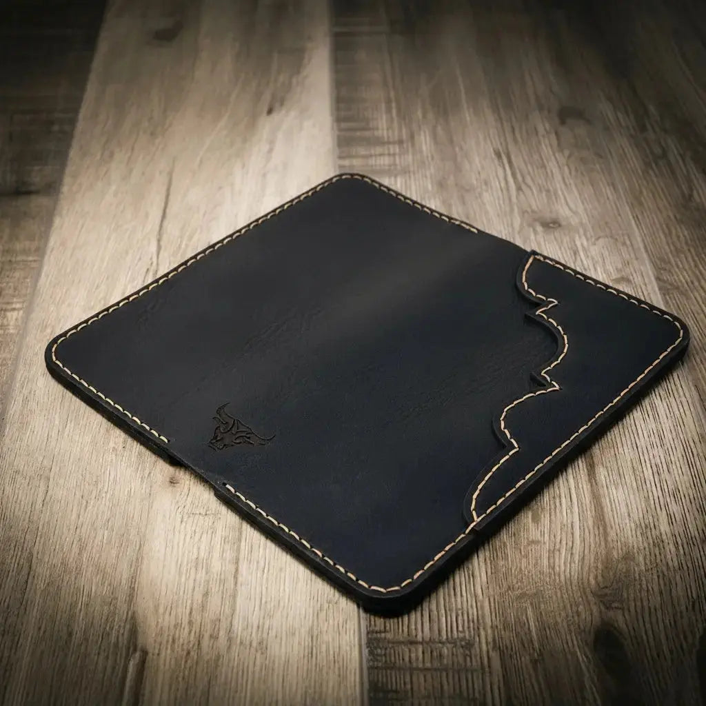 Black leather bifold wallet with a bull logo and decorative stitching on a wooden surface.