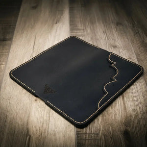 Black leather bifold wallet with a bull logo and decorative stitching on a wooden surface.