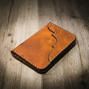 Brown leather bifold wallet with decorative stitching on a wooden background.