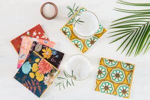 Set of four square cloth napkins with a blue and floral pattern and yellow trim.