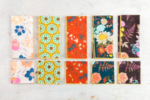 Collection of floral and patterned cloth napkins in various colors including orange, yellow, and teal.
