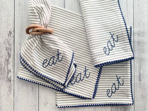 Striped fabric napkins with embroidered "EAT" and wooden bangle napkin rings.