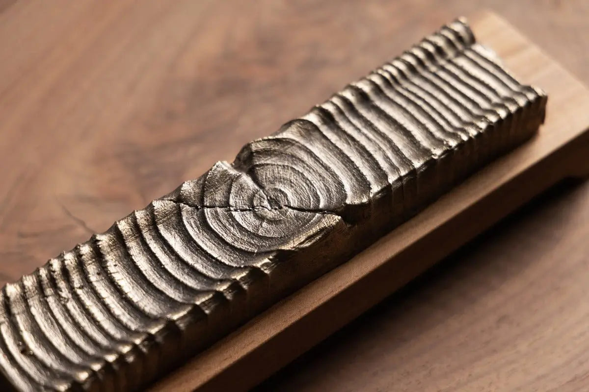 Handcrafted wood incense holder with bronze casting detail on a wooden surface.