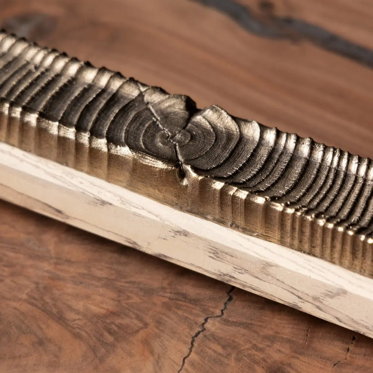 Wooden incense holder with bronze casting detail featuring carved rings and light wood base on wood surface.