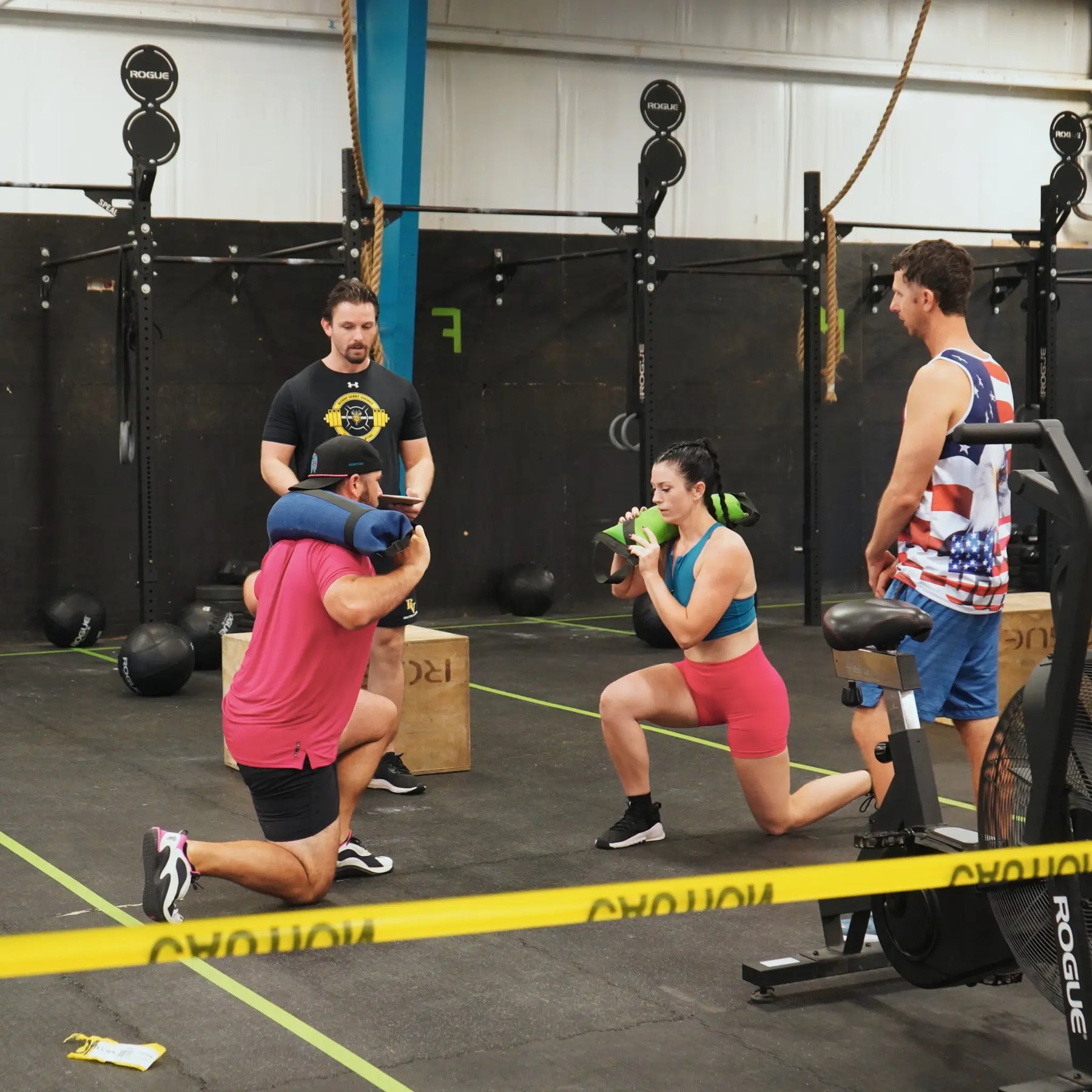 People using a sandbag for fitness training in a gym.