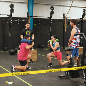 People using a sandbag for fitness training in a gym.