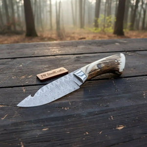 Handmade damascus steel knife with horn handle on dark surface