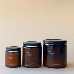 Three amber glass soy candles from ARC with gold + ivy scent in different sizes.