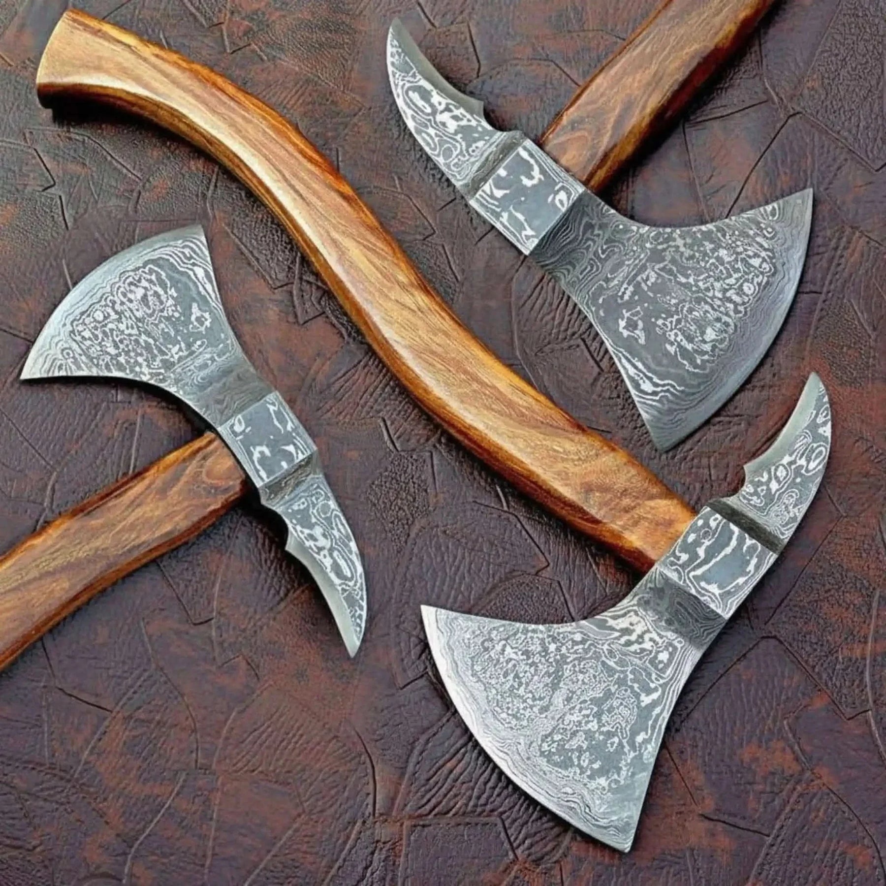 Damascus steel axe head with wood handle on rustic wood surface
