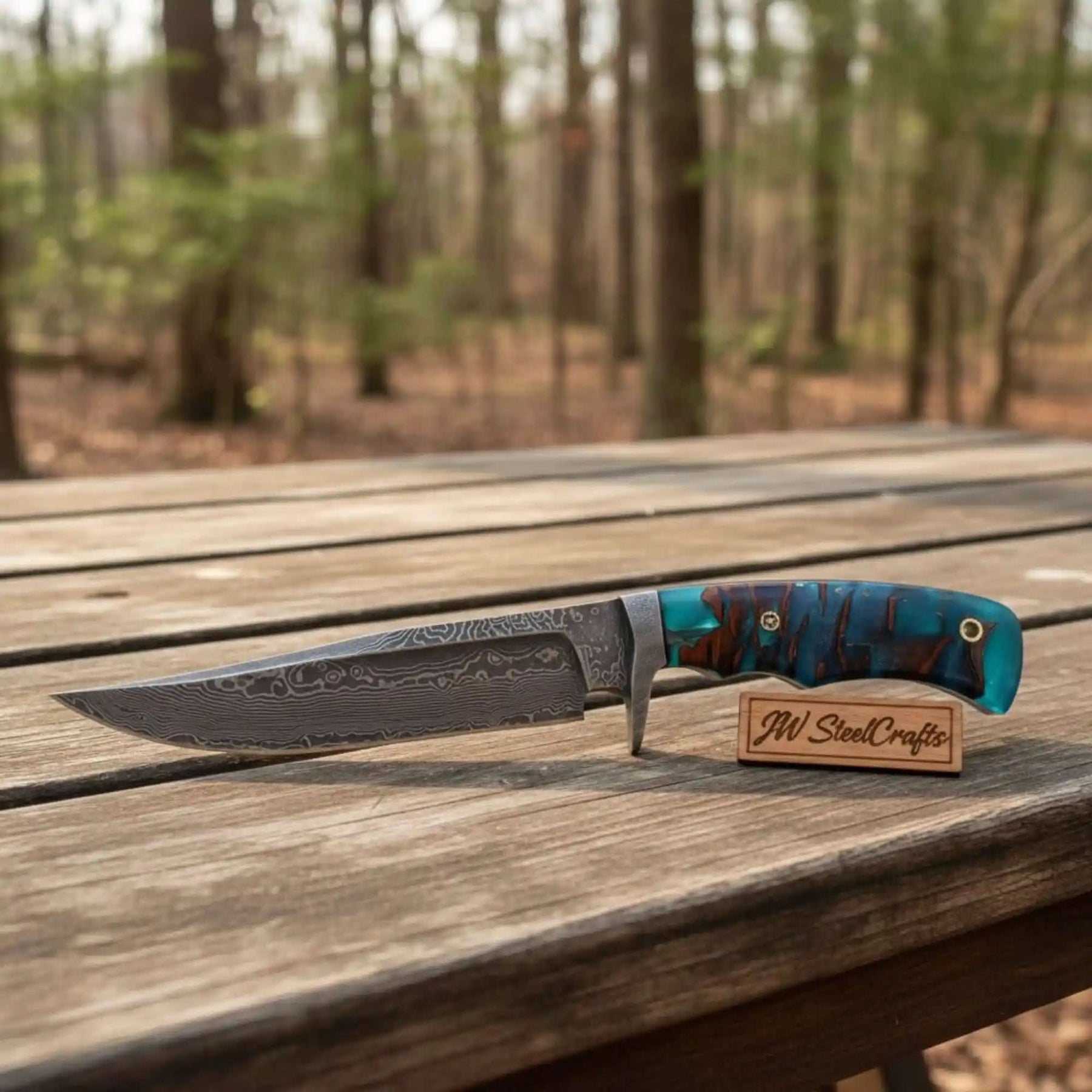 Handmade damascus steel knife with resin handle on dark surface