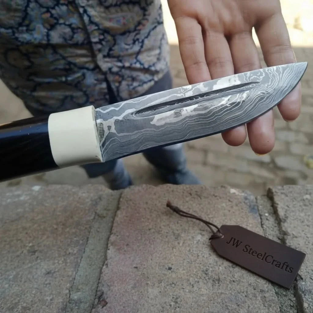 Handmade damascus steel knife with resin handle on dark surface
