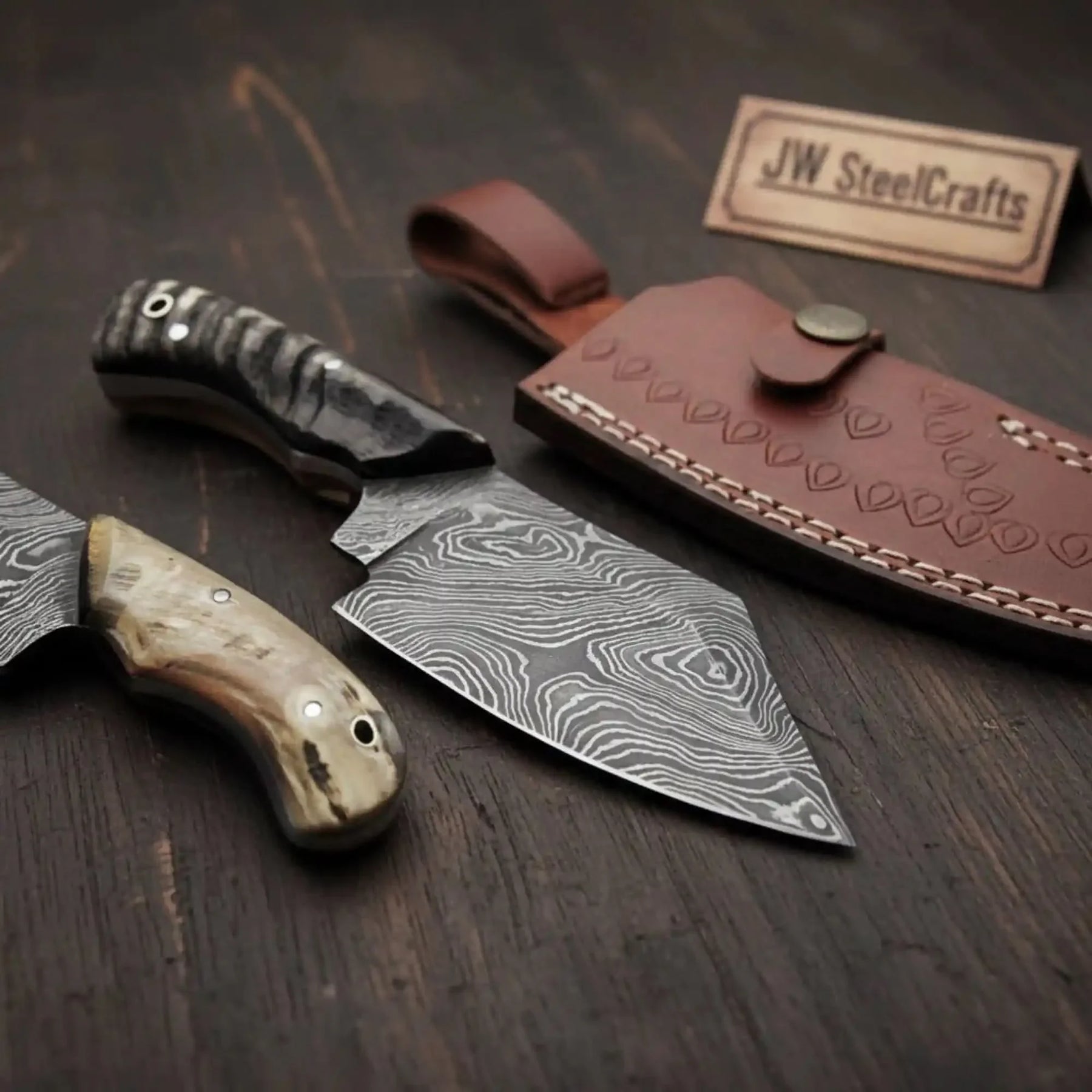 Handmade damascus steel knife with horn handle on dark surface