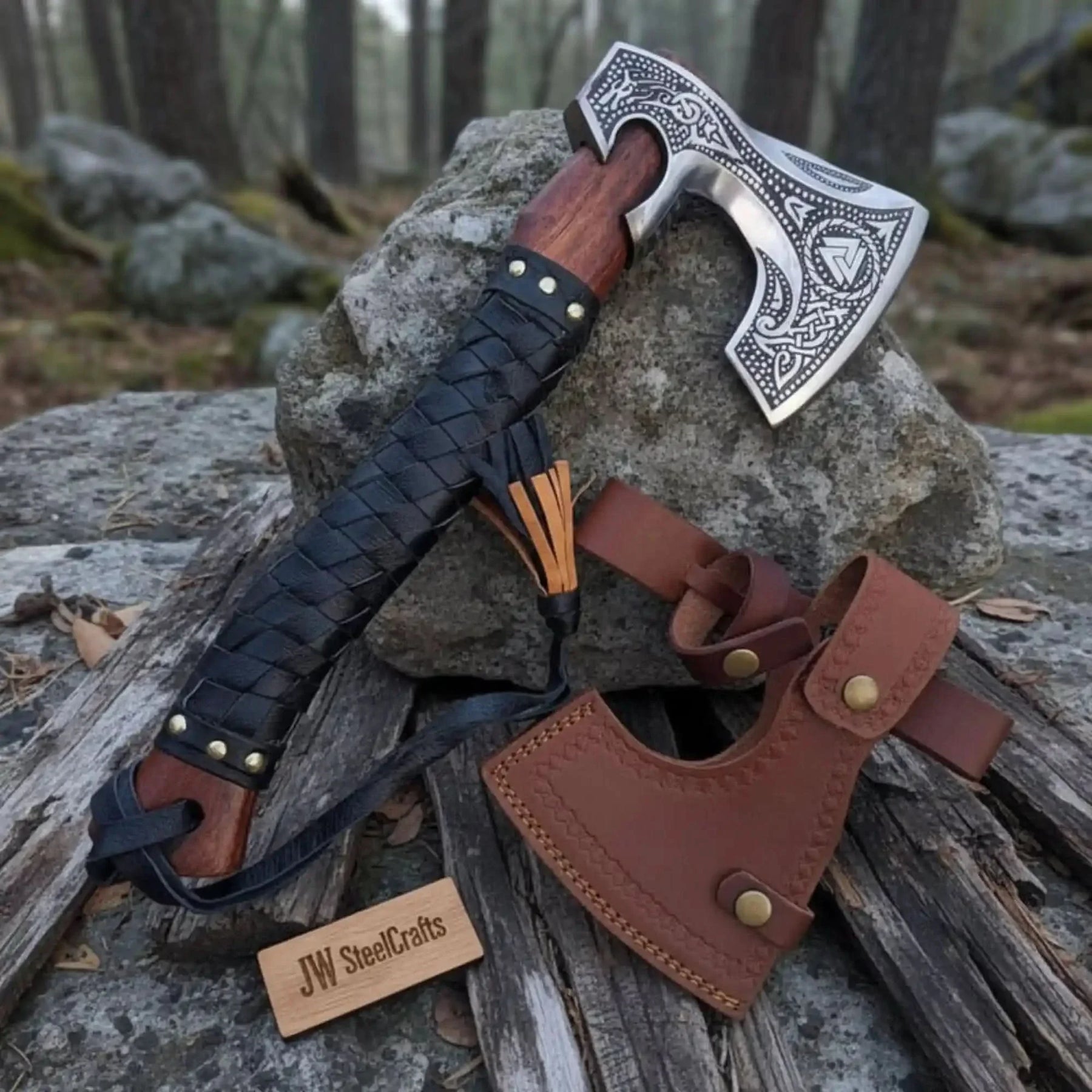 Damascus steel axe head with leather handle on rustic wood surface
