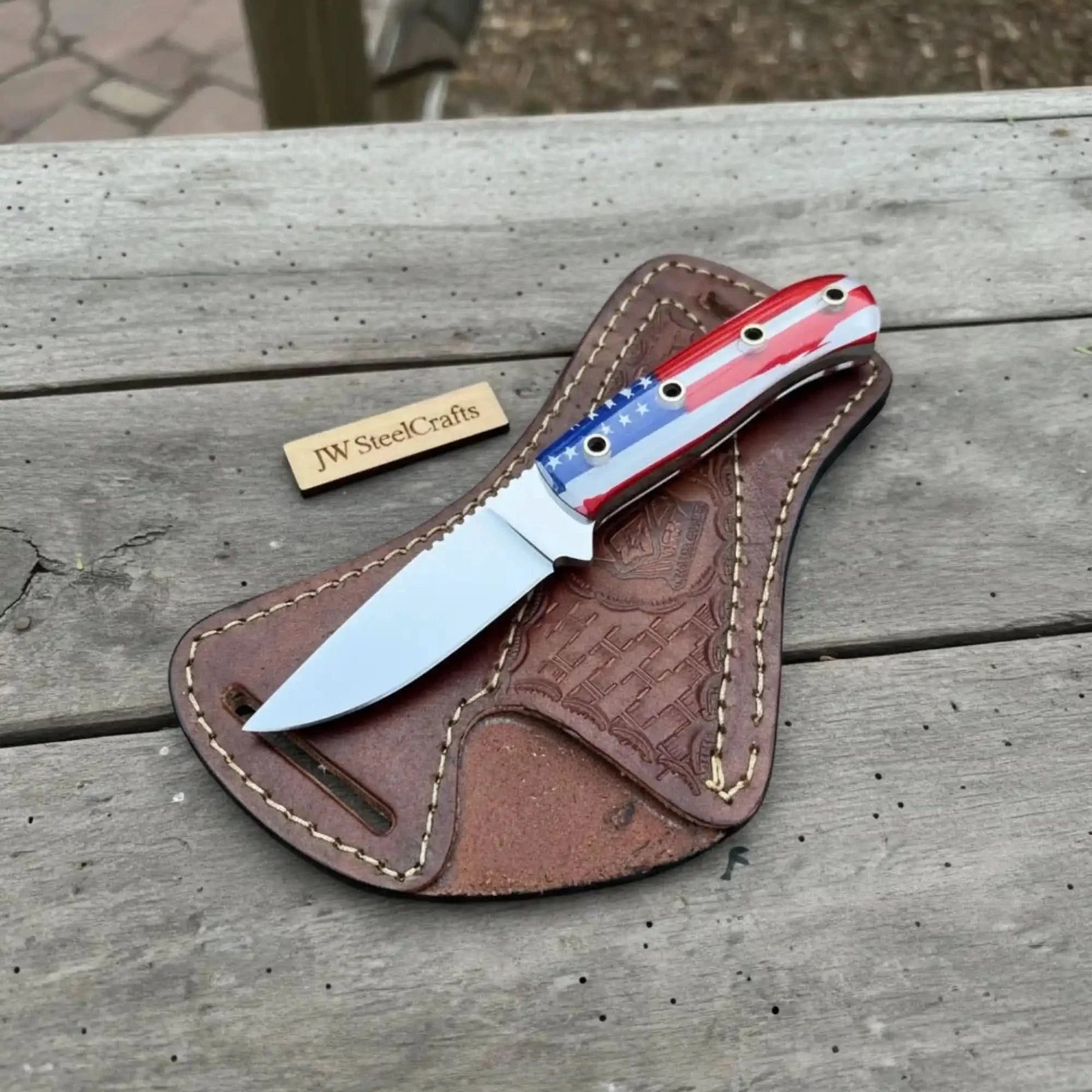 Handmade damascus steel knife with leather handle on dark surface
