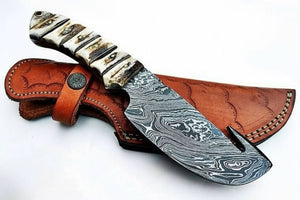 Handmade damascus steel knife with bone handle on dark surface