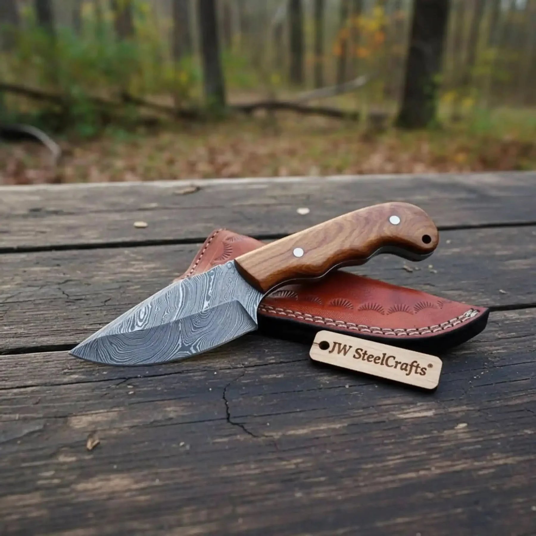 Handmade damascus steel knife with wood handle on dark surface