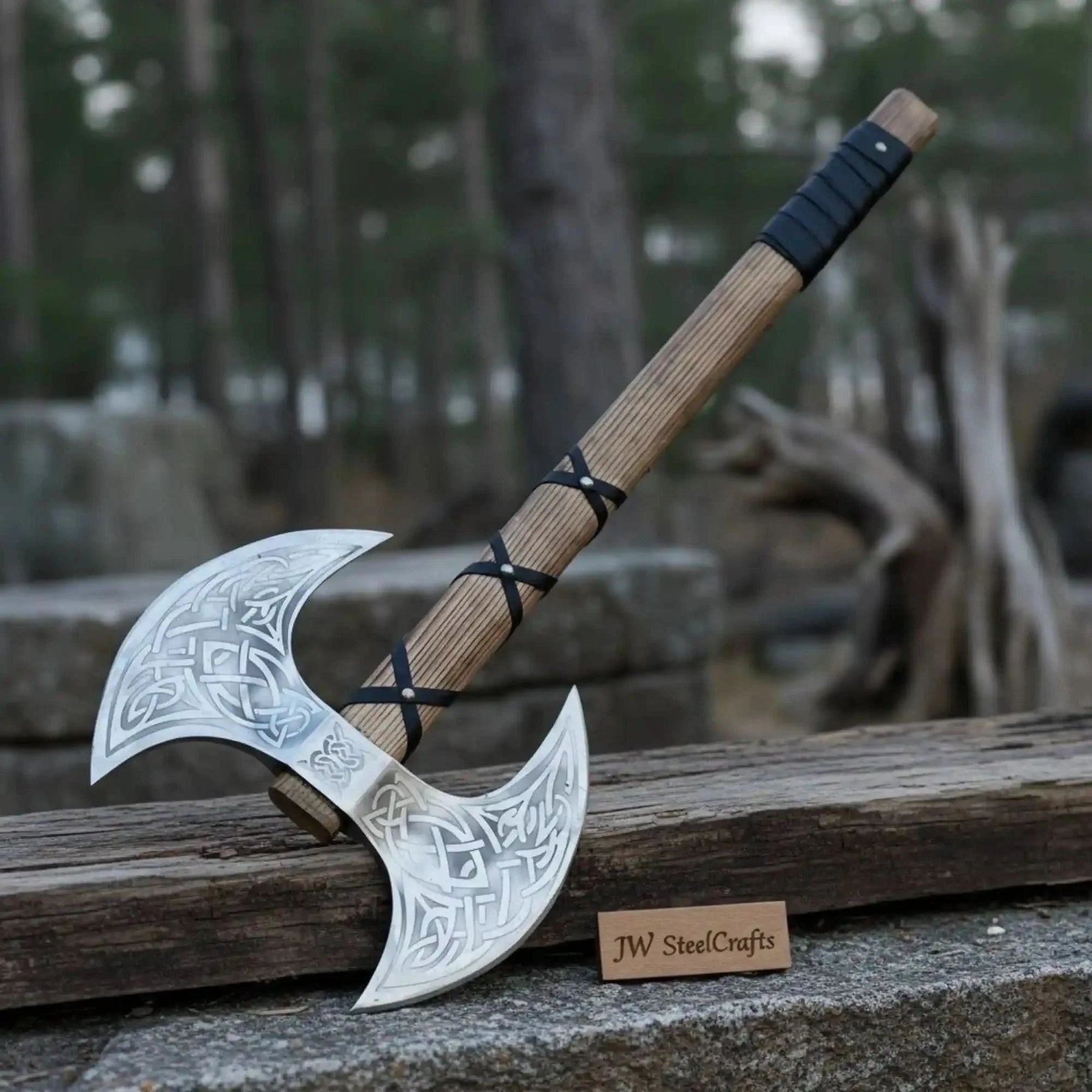 Damascus steel axe head with premium handle on rustic wood surface