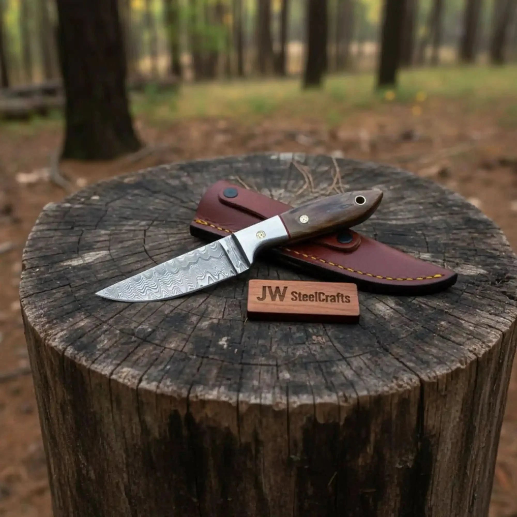 Handmade damascus steel knife with wood handle on dark surface