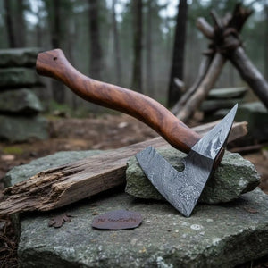 Damascus steel axe head with premium handle on rustic wood surface