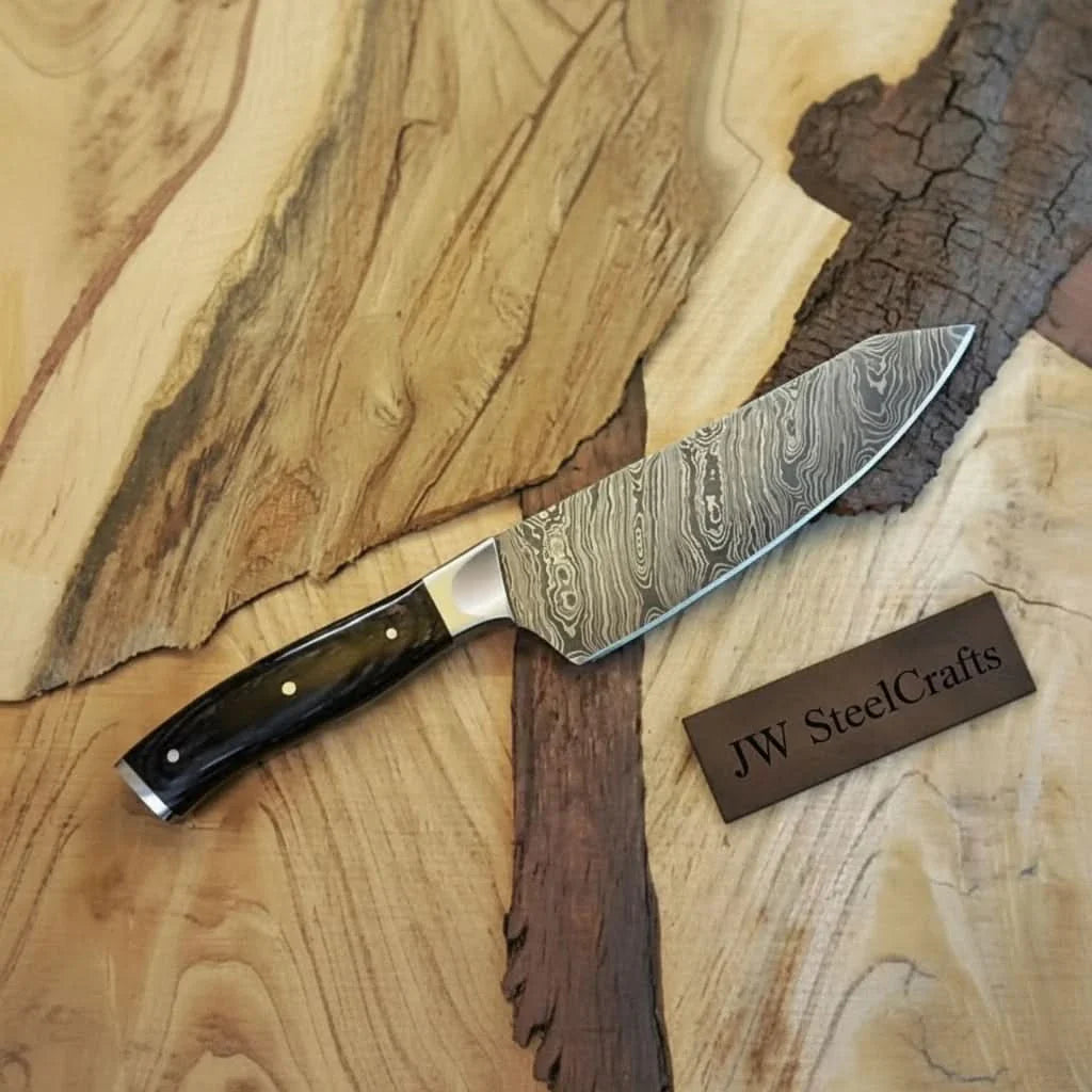 Handmade damascus steel knife with wood handle on dark surface