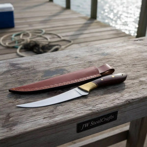 Handmade damascus steel knife with wood handle on dark surface
