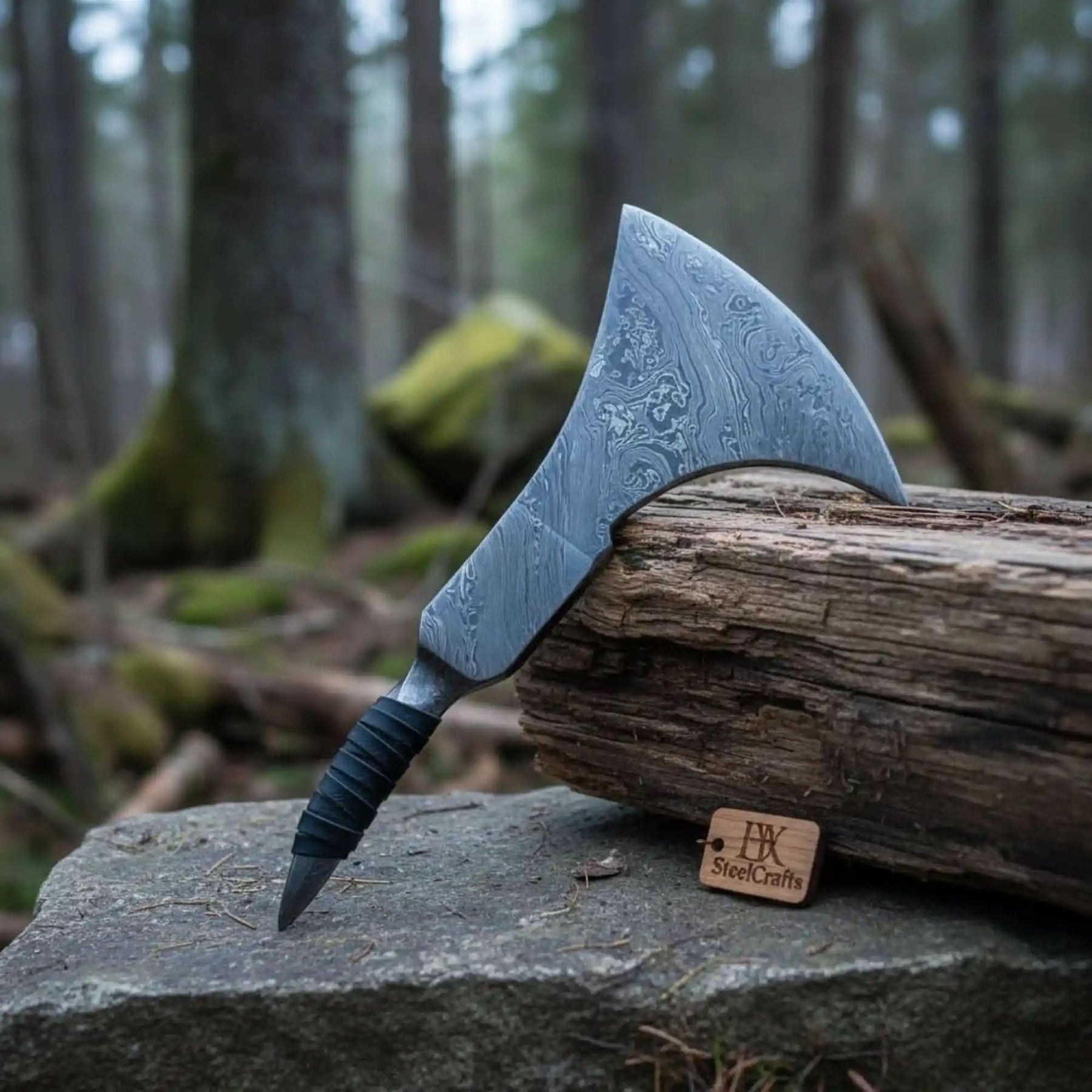 Damascus steel axe head with premium handle on rustic wood surface