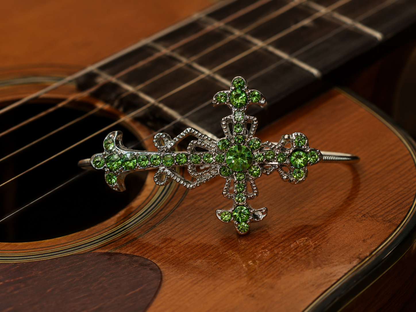 Decorative green gemstone cross on a guitar
