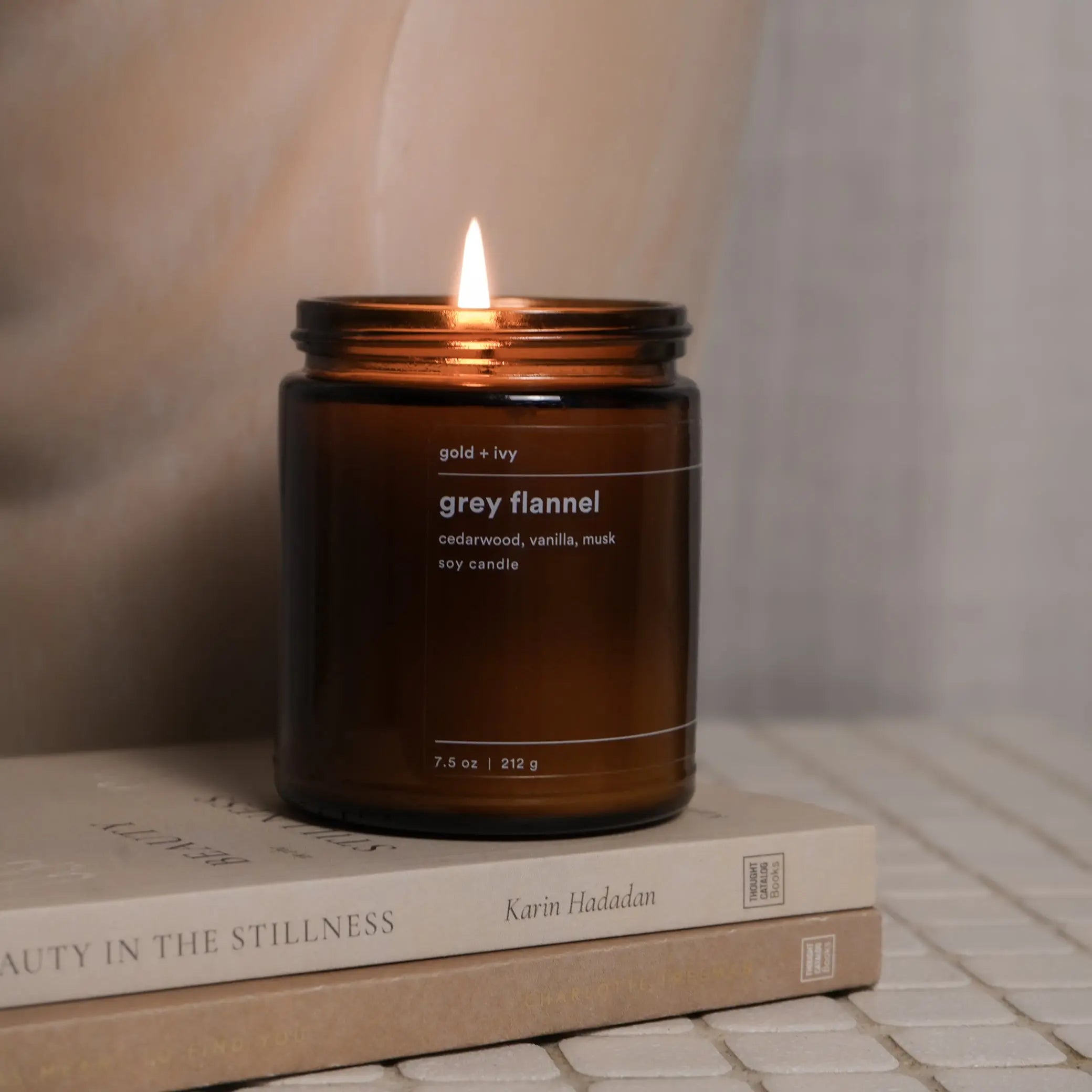 Grey flannel soy candle with cedarwood, vanilla, and musk notes in an amber glass jar.