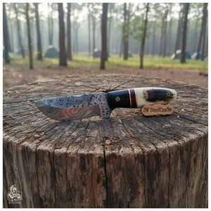 Handmade damascus steel knife with horn handle on dark surface
