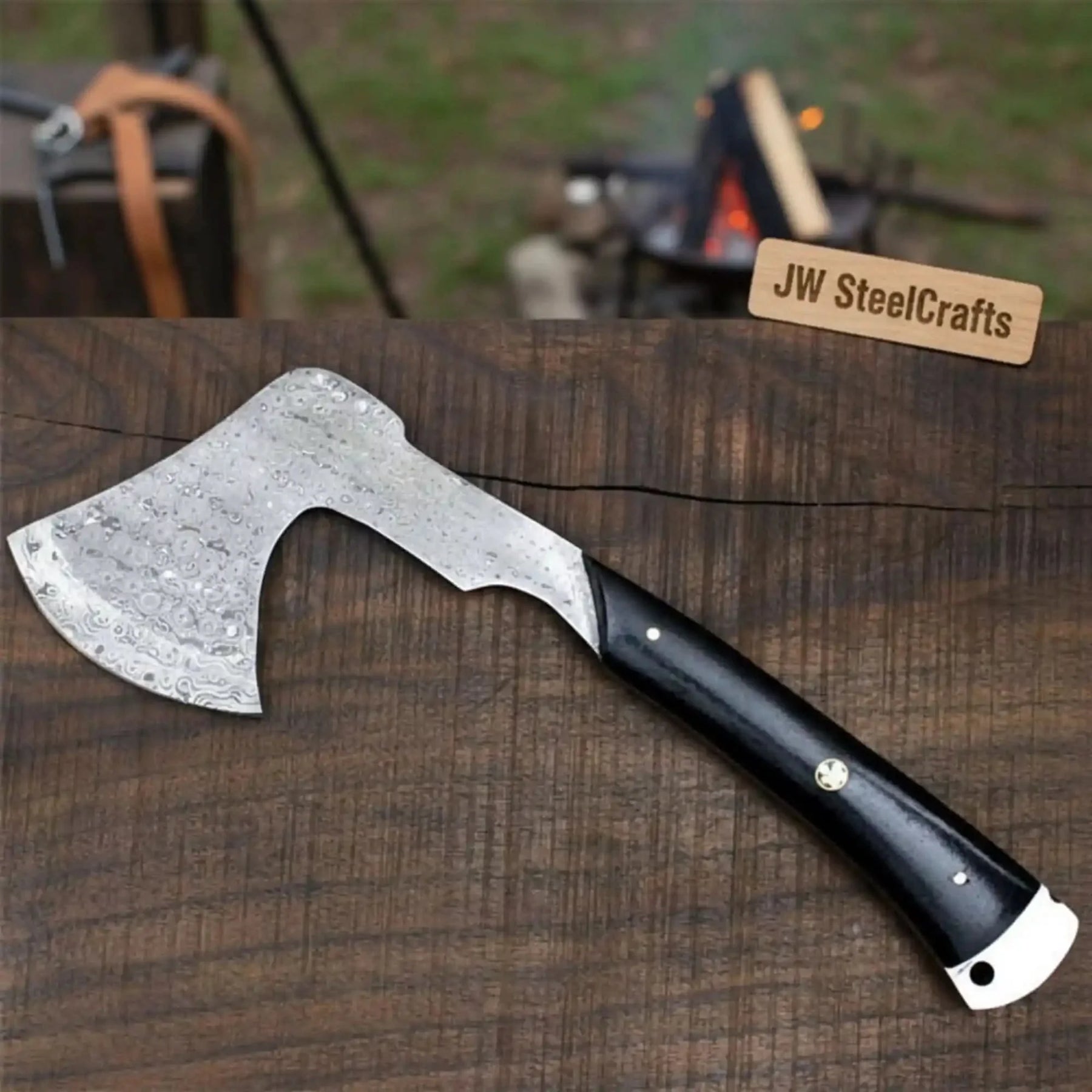 Damascus steel axe head with wood handle on rustic wood surface