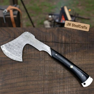 Damascus steel axe head with wood handle on rustic wood surface