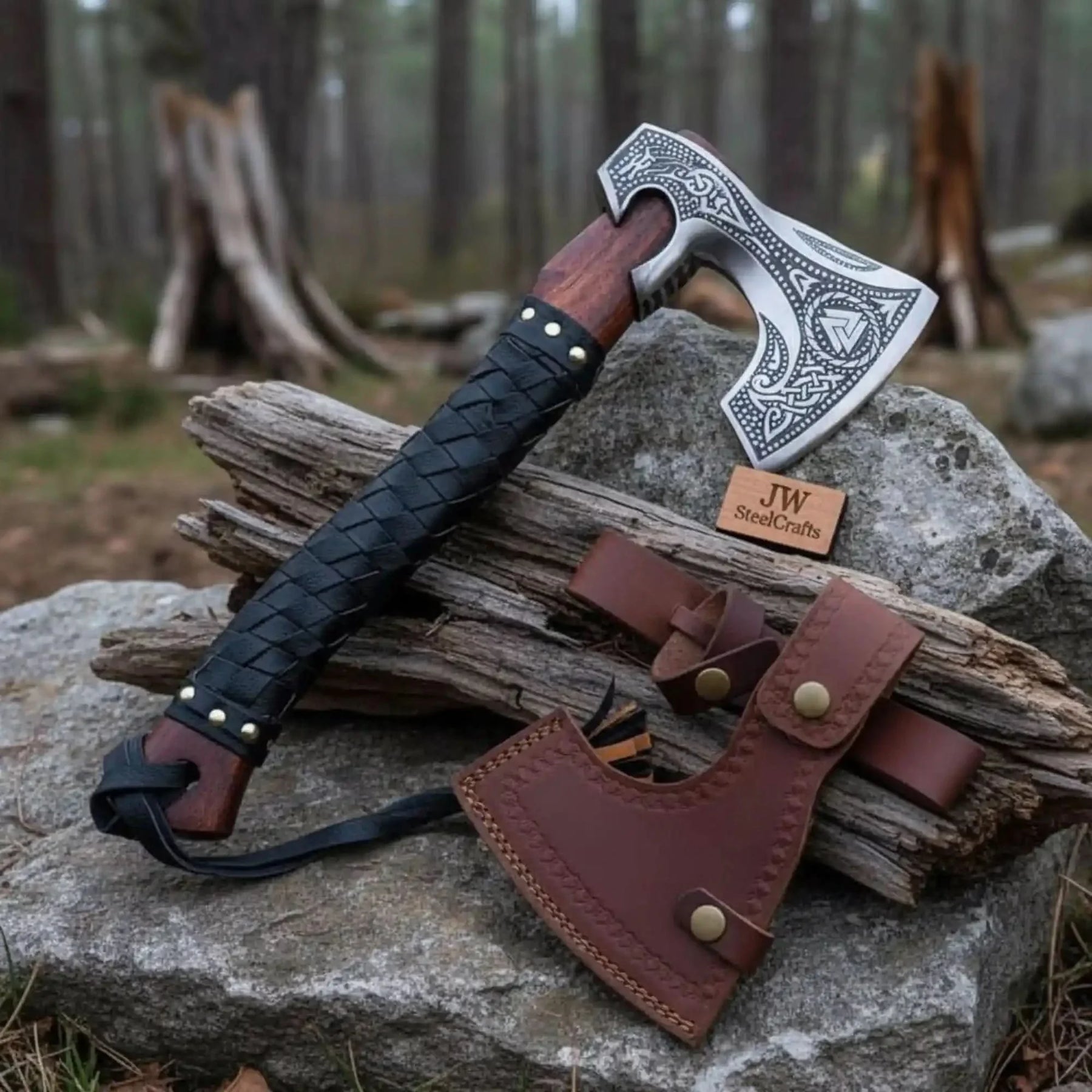 Damascus steel axe head with leather handle on rustic wood surface