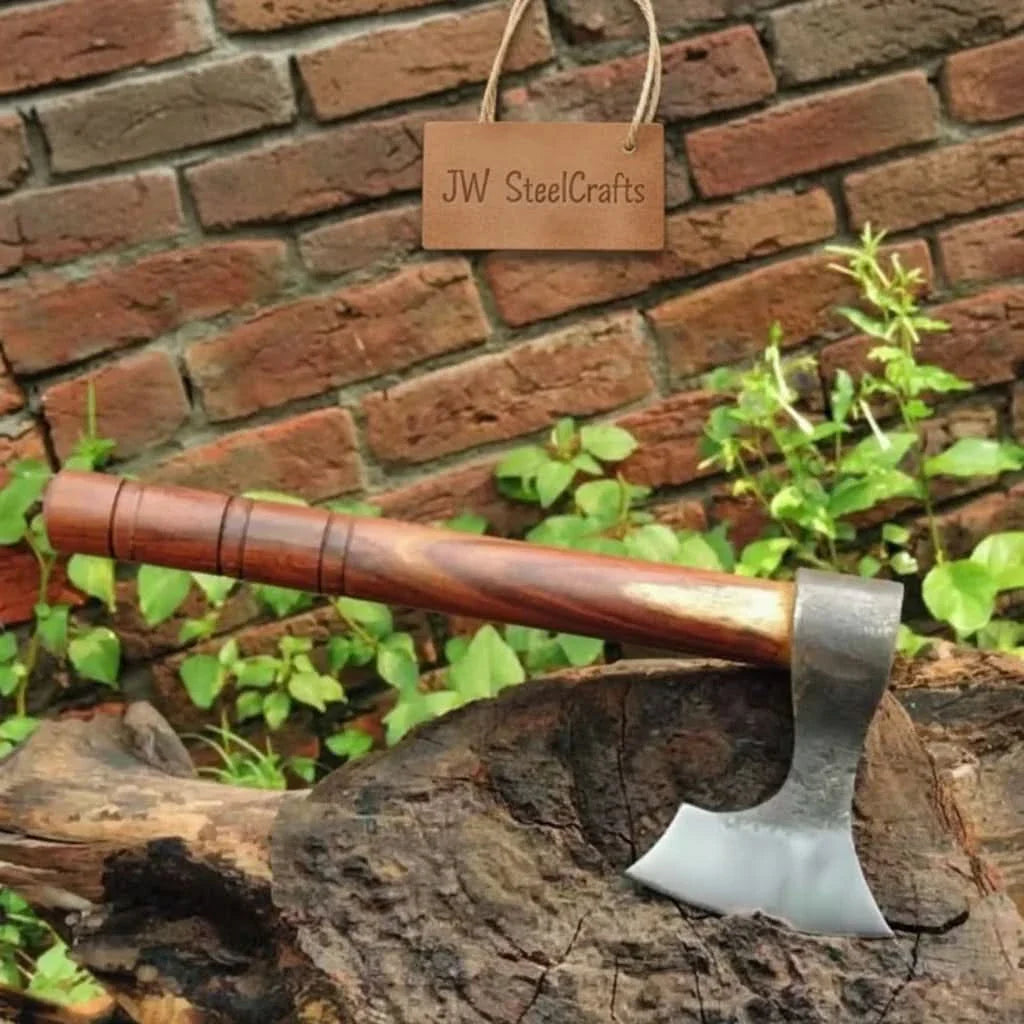 Damascus steel axe head with premium handle on rustic wood surface