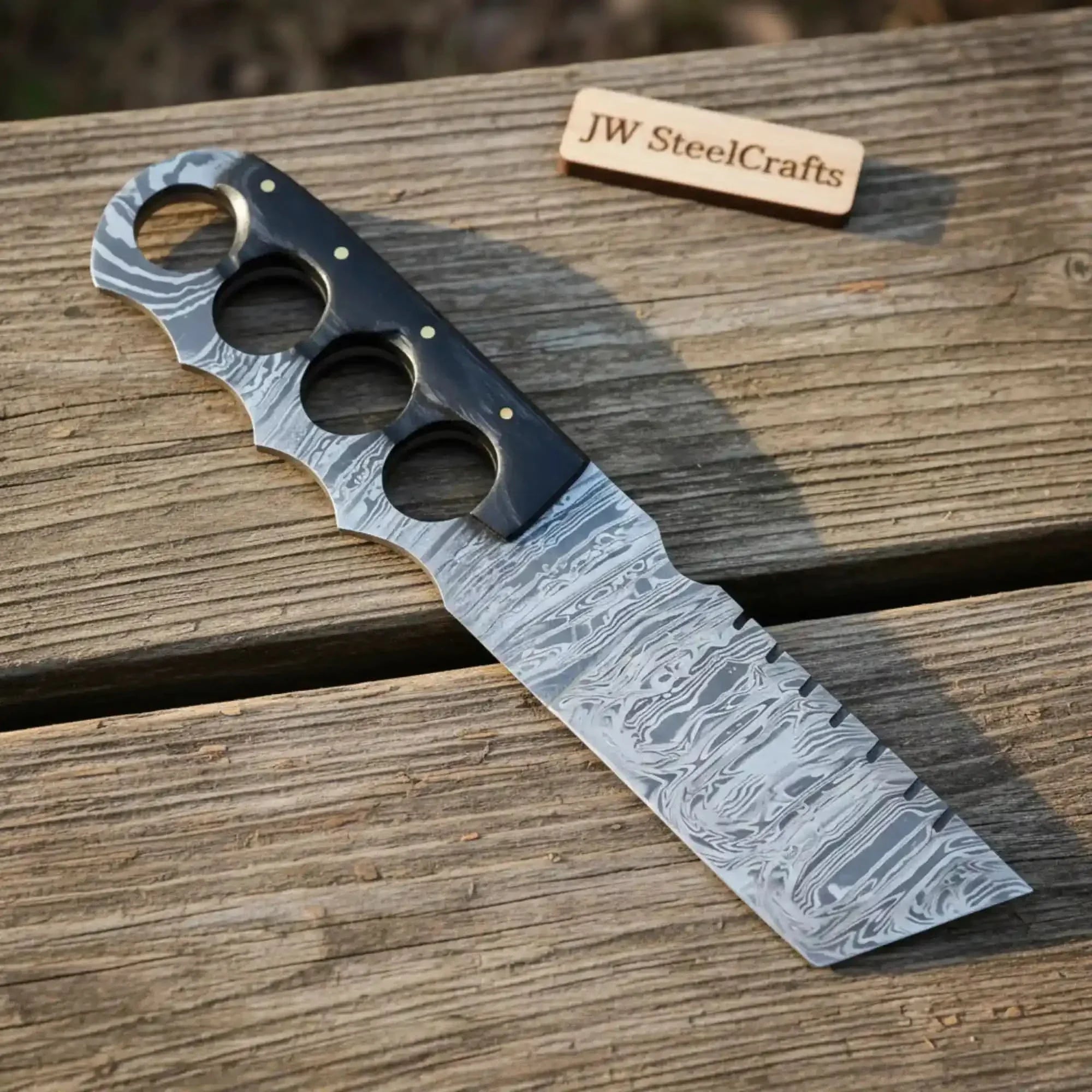 Handmade damascus steel knife with resin handle on dark surface